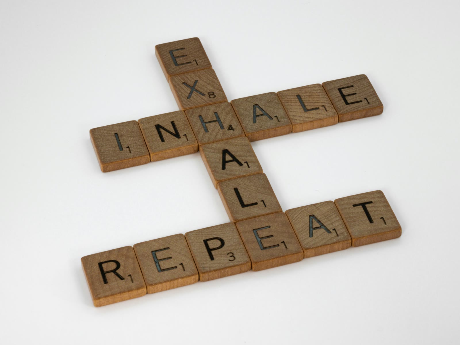 Drewniane kostki układające napis Inhale, Exhale, Repeat jako symbol pracy z oddechem